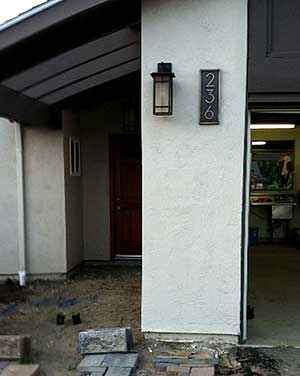 Vertical house number plaque on a stucco wall